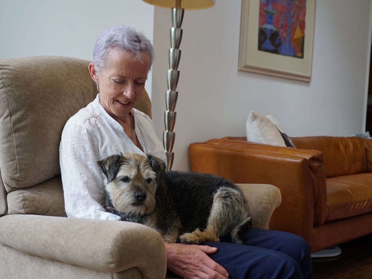 owner sitting on armchair with dog on their lap