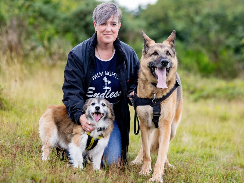 Dogs trust kenilworth worker Jo, posing with dogs Luka and Bingo, in a green field before they found their forever homes.