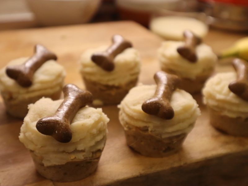 6 spiced apple celebration cupcakes with cream frosting and dog bone treats on top